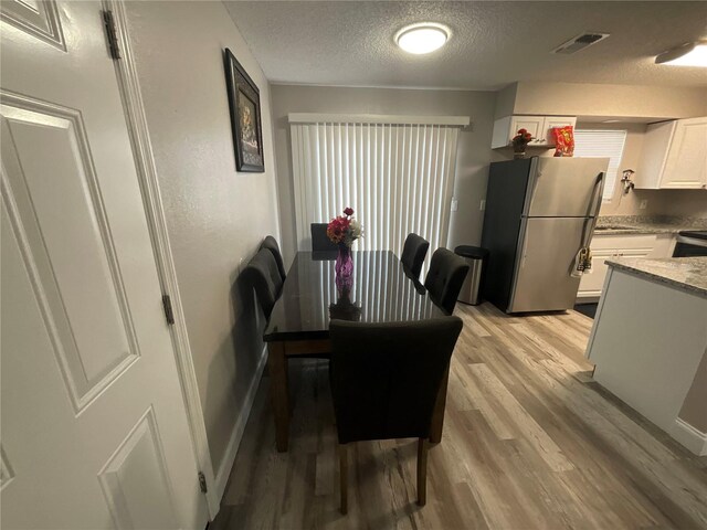 dining room with light hardwood / wood-style flooring and a textured ceiling