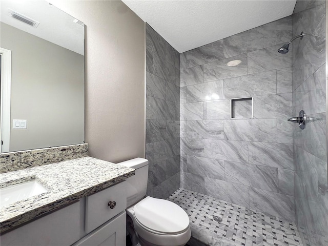 bathroom with vanity, toilet, and tiled shower