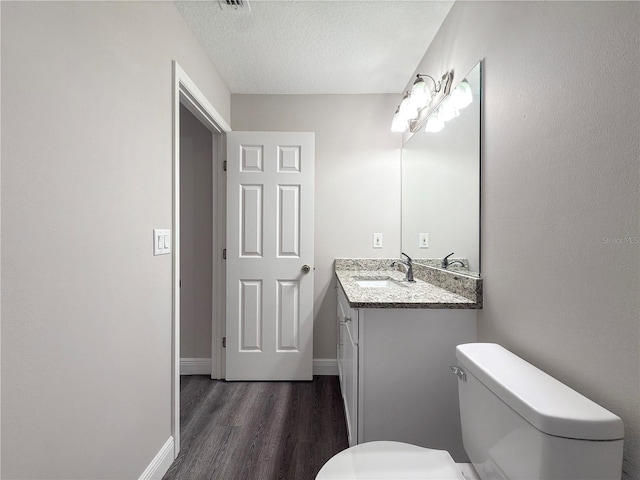 bathroom with vanity, toilet, wood-type flooring, and a textured ceiling