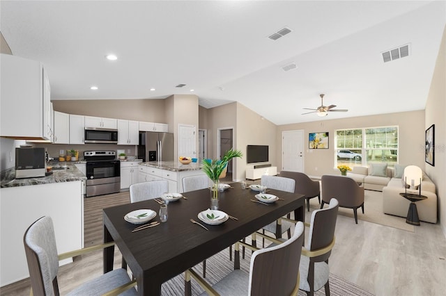 dining area with ceiling fan, lofted ceiling, and light hardwood / wood-style flooring