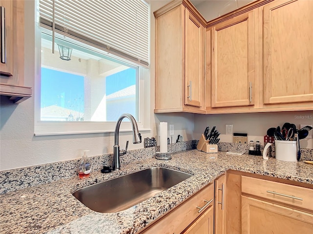 kitchen featuring light stone countertops, sink, and light brown cabinets