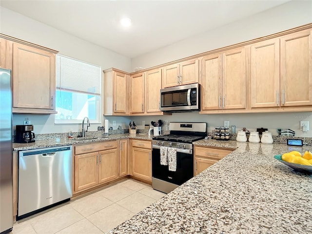 kitchen with light brown cabinets, sink, light tile patterned floors, light stone counters, and stainless steel appliances