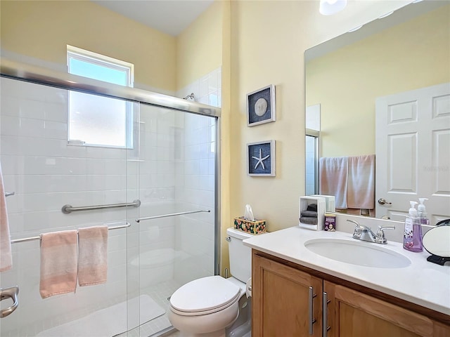 bathroom featuring vanity, toilet, and a shower with door