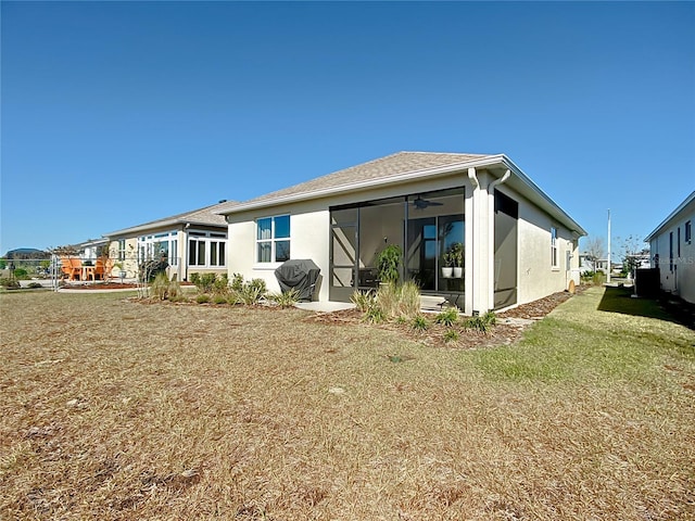 rear view of house featuring a sunroom and a yard