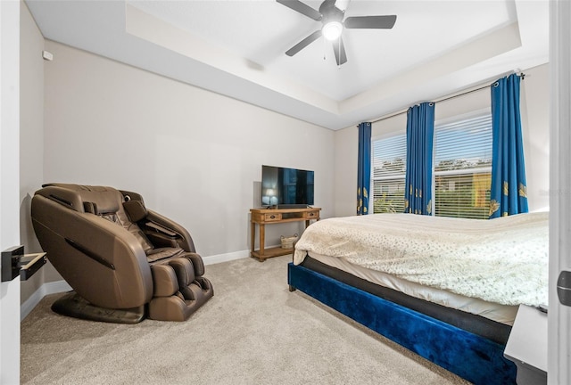 carpeted bedroom featuring a tray ceiling and ceiling fan