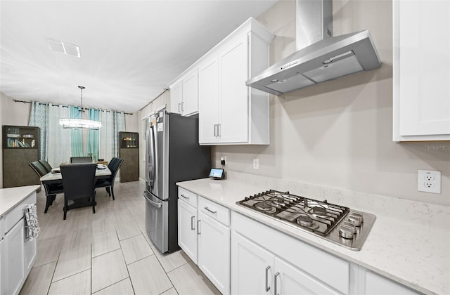 kitchen with white cabinetry, a chandelier, wall chimney range hood, and appliances with stainless steel finishes