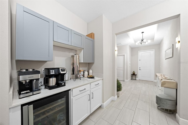 kitchen featuring pendant lighting, a textured ceiling, an inviting chandelier, and beverage cooler