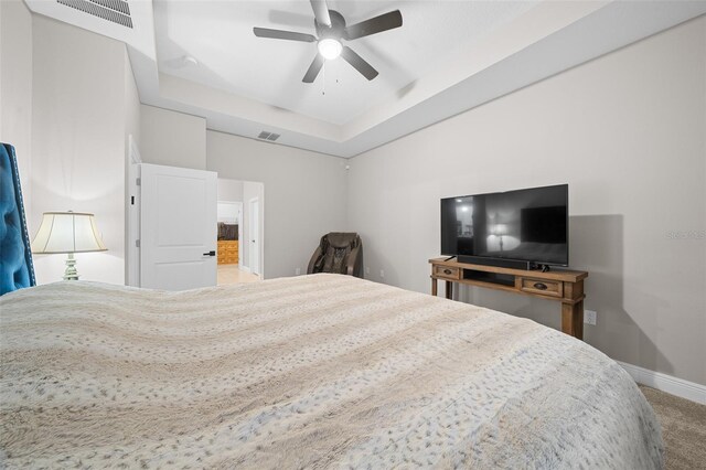 carpeted bedroom with a tray ceiling and ceiling fan