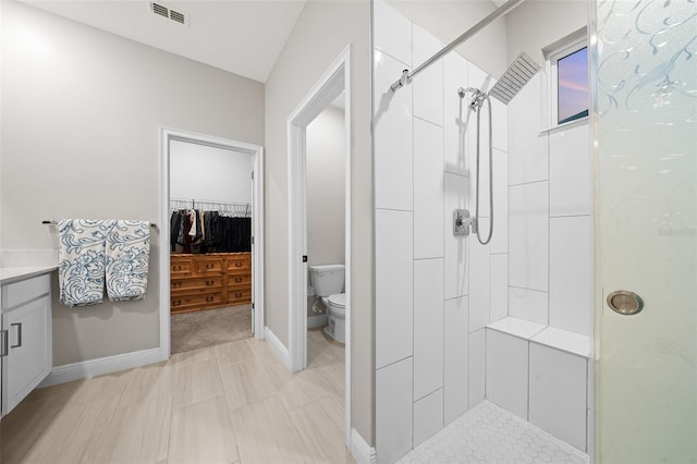 bathroom featuring toilet, vanity, and tiled shower