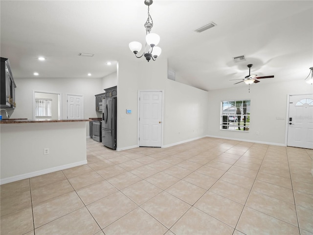 unfurnished living room featuring ceiling fan with notable chandelier, vaulted ceiling, and light tile patterned flooring