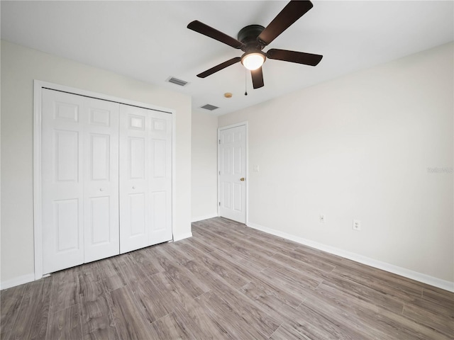 unfurnished bedroom with ceiling fan, a closet, and light wood-type flooring