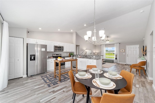 dining area featuring sink, high vaulted ceiling, ceiling fan with notable chandelier, and light wood-type flooring