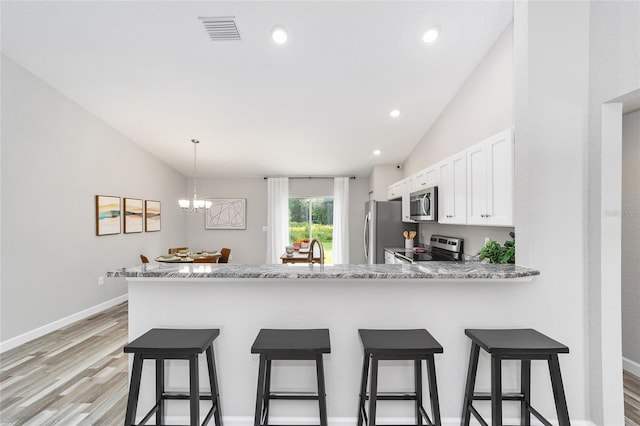 kitchen featuring white cabinetry, stainless steel appliances, light hardwood / wood-style flooring, kitchen peninsula, and vaulted ceiling