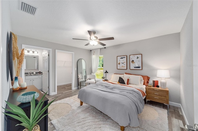 bedroom with a walk in closet, ceiling fan, a closet, and light hardwood / wood-style flooring