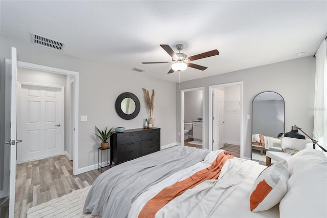 bedroom featuring connected bathroom, ceiling fan, light hardwood / wood-style flooring, a walk in closet, and a closet