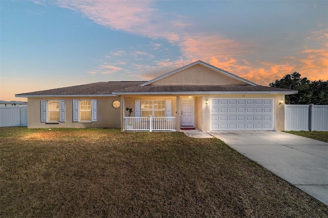 ranch-style home featuring covered porch, a garage, and a lawn