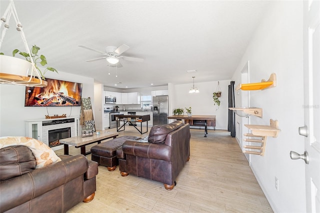 living room with ceiling fan, light hardwood / wood-style flooring, and a textured ceiling