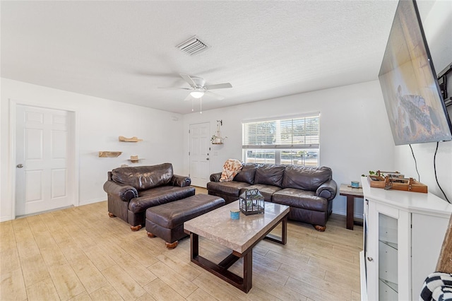 living room with a textured ceiling, light hardwood / wood-style floors, and ceiling fan