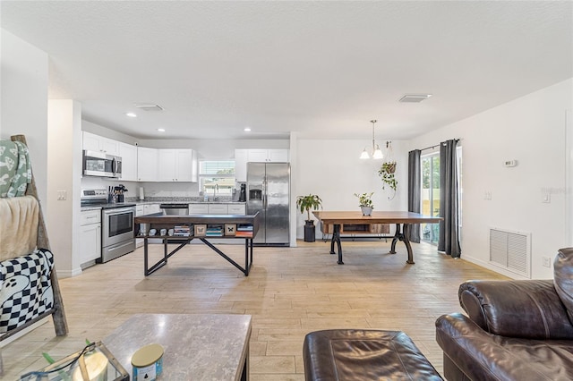 interior space with plenty of natural light, a chandelier, and light hardwood / wood-style flooring