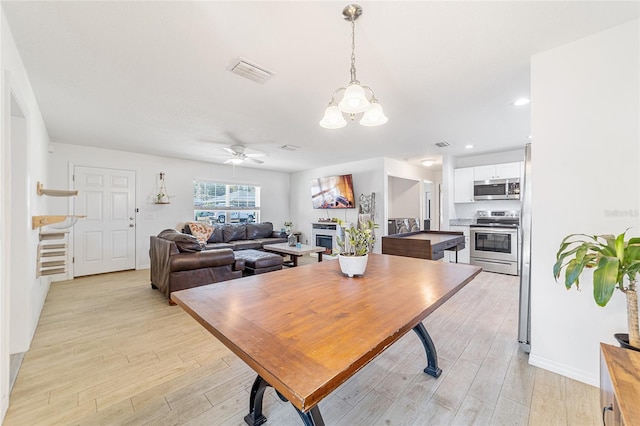 dining area featuring ceiling fan with notable chandelier and light wood-type flooring