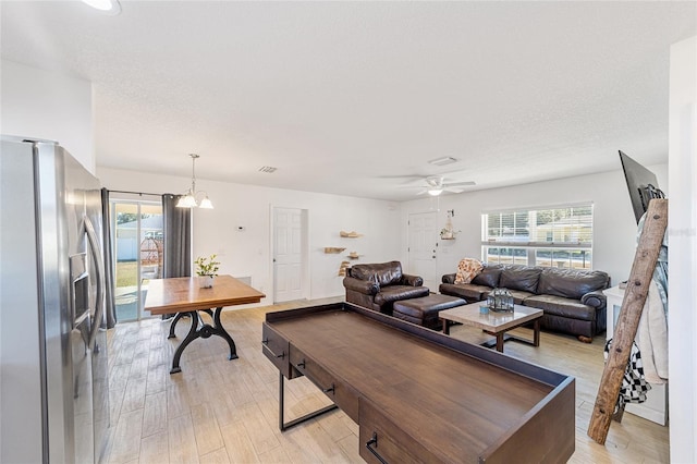 living room featuring a textured ceiling, light hardwood / wood-style flooring, and ceiling fan with notable chandelier