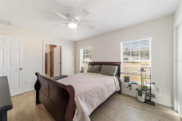 bedroom with multiple windows, ceiling fan, light hardwood / wood-style flooring, and a textured ceiling