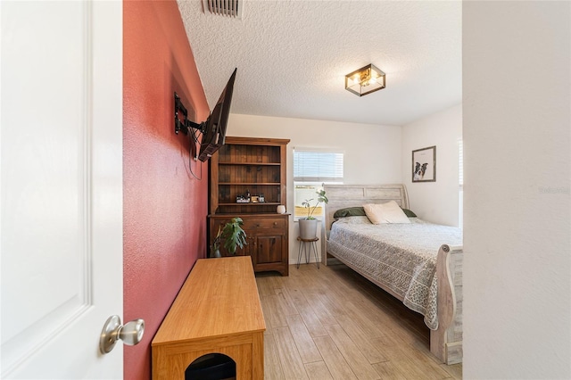 bedroom with light hardwood / wood-style floors and a textured ceiling