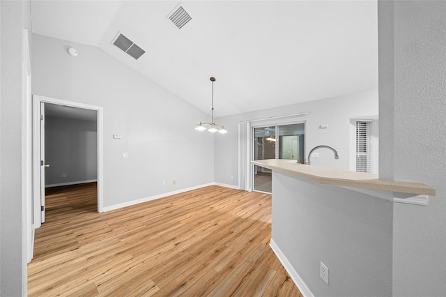 interior space featuring a notable chandelier, light wood-type flooring, and lofted ceiling