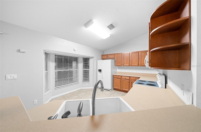 kitchen with sink, kitchen peninsula, vaulted ceiling, white appliances, and light tile patterned floors