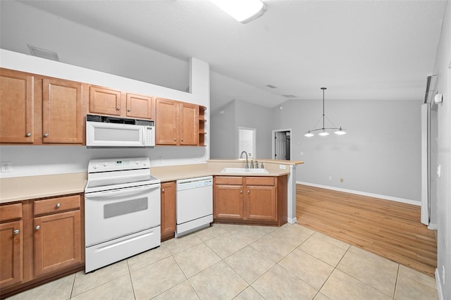 kitchen with pendant lighting, white appliances, sink, vaulted ceiling, and light hardwood / wood-style floors