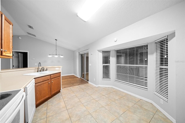 kitchen featuring white appliances, sink, vaulted ceiling, decorative light fixtures, and light tile patterned flooring