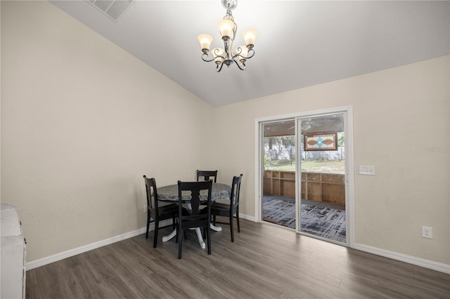 dining space with dark wood-type flooring, lofted ceiling, and a notable chandelier