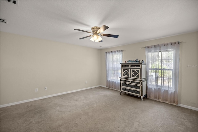 carpeted spare room featuring ceiling fan and a textured ceiling