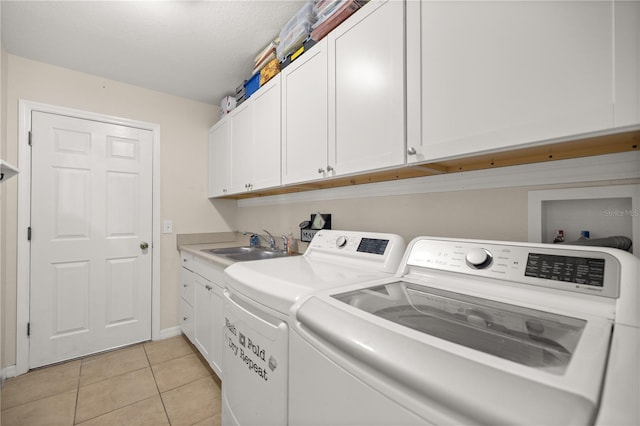 laundry area featuring cabinets, a textured ceiling, sink, light tile patterned floors, and washing machine and clothes dryer