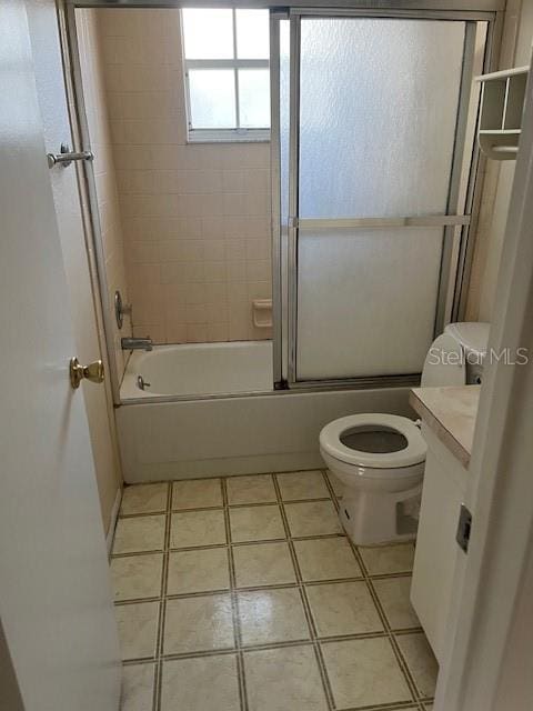 full bathroom featuring tile patterned flooring, toilet, combined bath / shower with glass door, and vanity