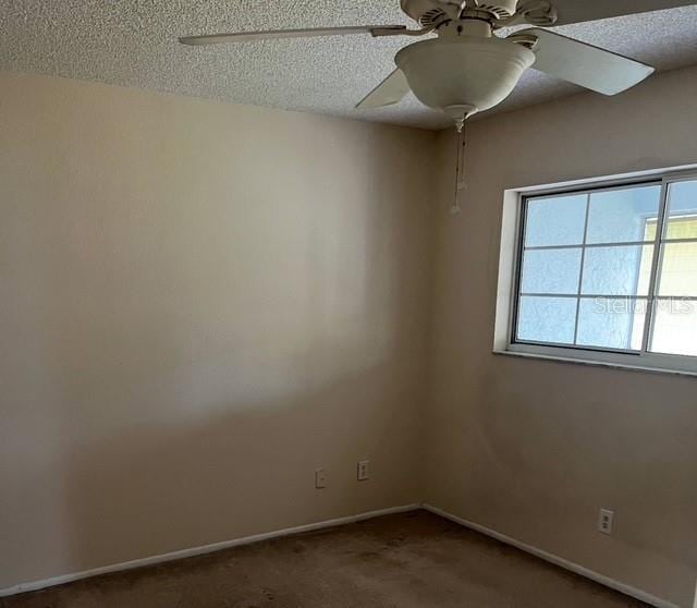 carpeted spare room featuring a textured ceiling and ceiling fan