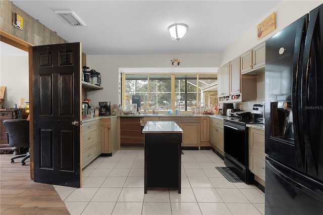 kitchen with cream cabinets, a center island, and black appliances