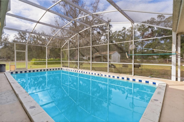 view of swimming pool featuring glass enclosure, a storage shed, and a yard