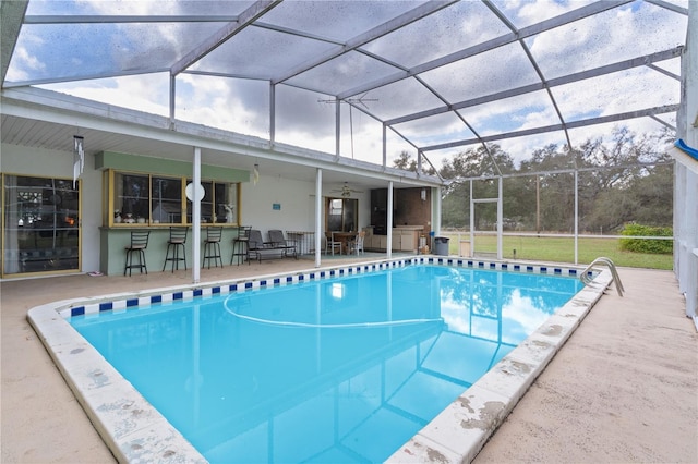 view of swimming pool featuring glass enclosure, an outdoor bar, and a patio