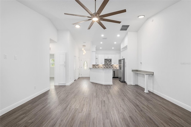 unfurnished living room with ceiling fan, dark hardwood / wood-style flooring, and lofted ceiling