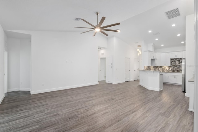 unfurnished living room with hardwood / wood-style floors, high vaulted ceiling, and ceiling fan