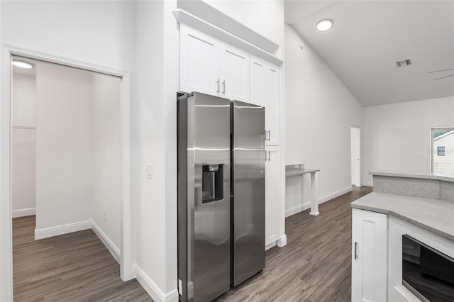 kitchen featuring vaulted ceiling, stainless steel fridge with ice dispenser, ceiling fan, dark hardwood / wood-style flooring, and white cabinetry