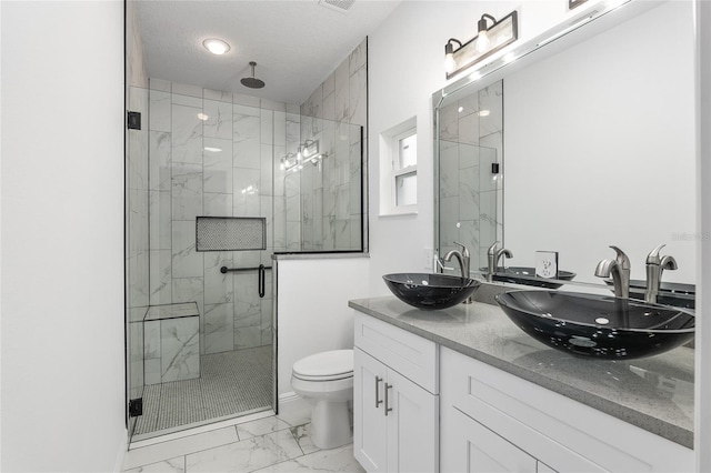 bathroom with a textured ceiling, vanity, toilet, and a shower with shower door