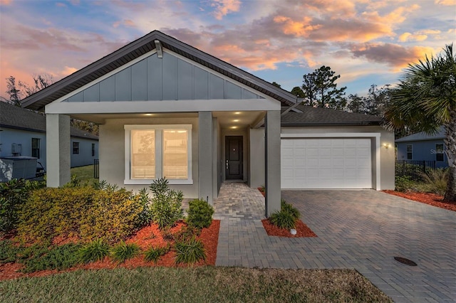 view of front of property with a porch, a garage, and central air condition unit