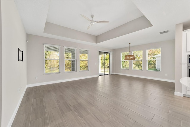 unfurnished living room featuring ceiling fan and a tray ceiling