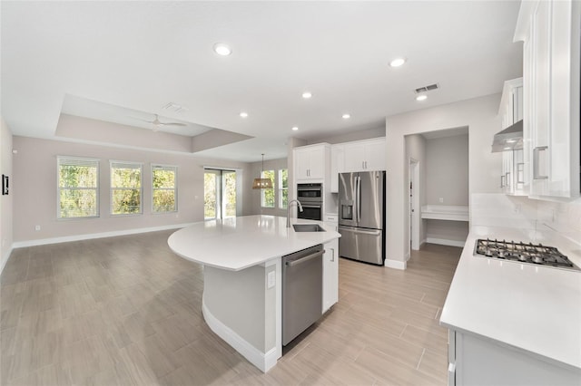 kitchen with ceiling fan, hanging light fixtures, stainless steel appliances, an island with sink, and white cabinets