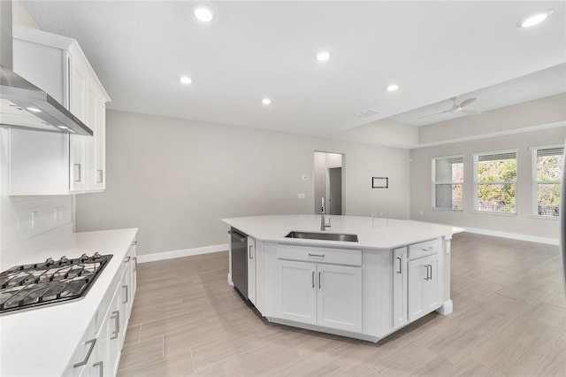 kitchen with white cabinets, a kitchen island with sink, sink, and wall chimney exhaust hood