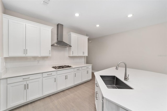 kitchen featuring white cabinetry, sink, wall chimney range hood, tasteful backsplash, and stainless steel gas stovetop