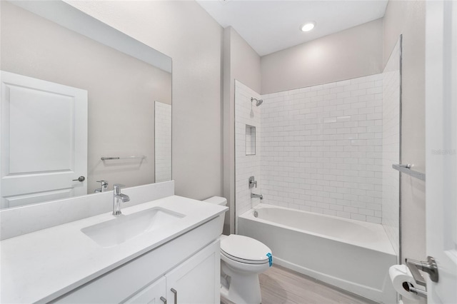 full bathroom with vanity, toilet, tiled shower / bath, and hardwood / wood-style flooring