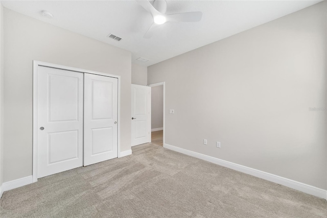 unfurnished bedroom with ceiling fan, light carpet, and a closet